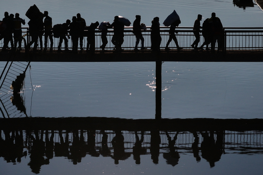 FILE - Displaced Syrians walk to cross at a river crossing near the village of Rasm al-Harmil al-Imam in the eastern Aleppo countryside, near the front line with the Kurdish-led Syrian Democratic Forces, in Deir Hafer, Syria, Friday, Jan. 16, 2026. (AP Photo/Ghaith Alsayed)