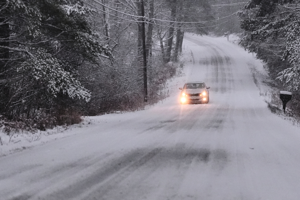 A car rolls down a snow covered road during a winter storm, Tuesday, Dec. 2, 2025, in East Derry, N.H. (AP Photo/Charles Krupa)