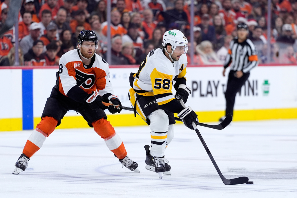 Pittsburgh Penguins' Kris Letang, right, tries to get past Philadelphia Flyers' Cam York during the first period of Game 4 in the first round of the NHL Stanley Cup hockey playoffs Saturday, April 25, 2026, in Philadelphia. (AP Photo/Matt Slocum)