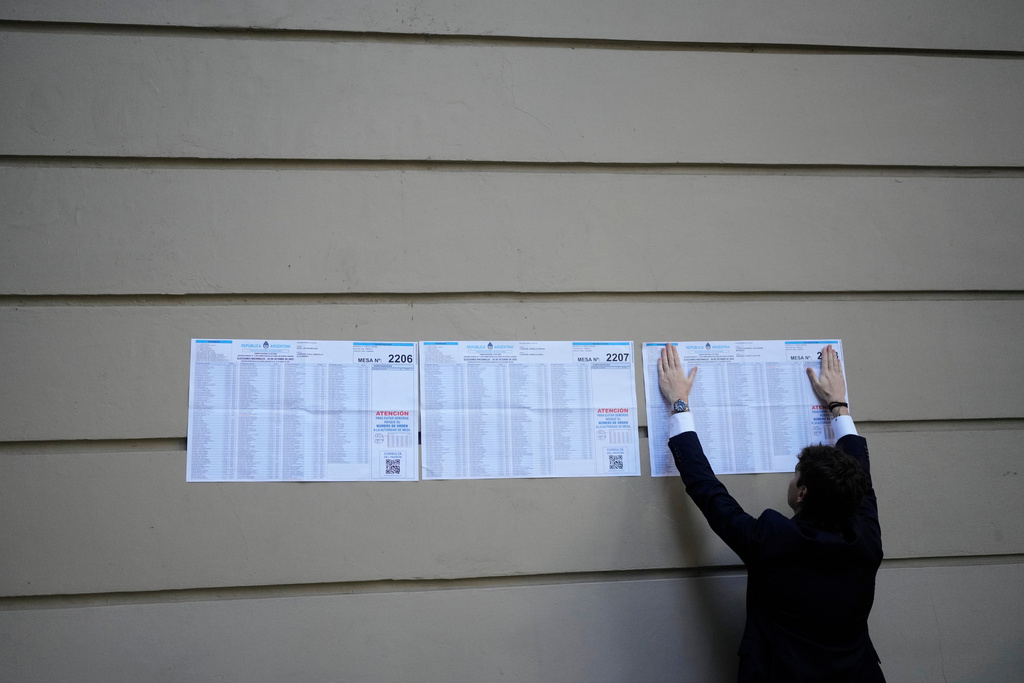 An electoral official places electoral rolls outside a polling station during legislative midterm elections in Buenos Aires, Argentina, Sunday, Oct. 26, 2025. (AP Photo/Natacha Pisarenko)
