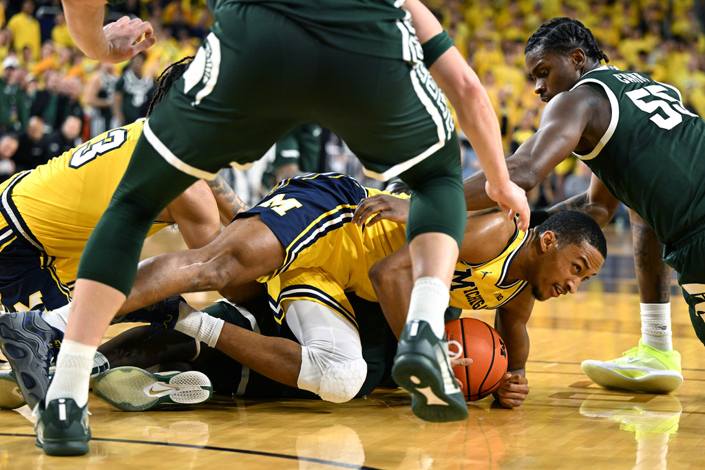 Michigan guard Nimari Burnett battles for a loose ball with Michigan State forward Coen Carr (55) in the first half of an NCAA college basketball game in Ann Arbor, Mich., Sunday, March 8, 2026. (AP Photo/Lon Horwedel)