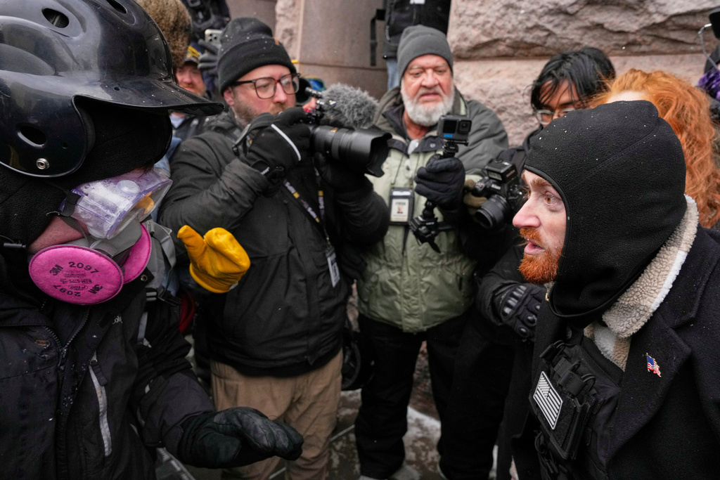 A pro-immigration protester, left, clashes with a man attending the March Against Minnesota Fraud, right, in front of Minneapolis City Hall, Saturday, Jan. 17, 2026, in Minneapolis. (AP Photo/Yuki Iwamura)