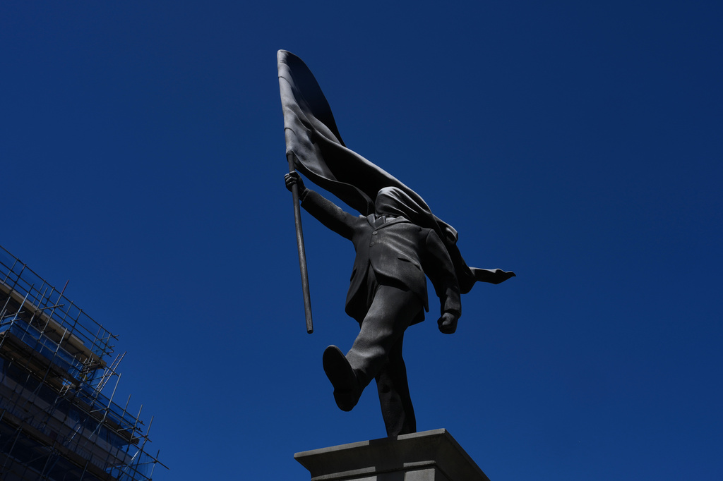 A statue of a man holding a flag covering his face, and signed 'Banksy', which has appeared in Waterloo Place in London, Thursday, April 30, 2026. (AP Photo/Kin Cheung)