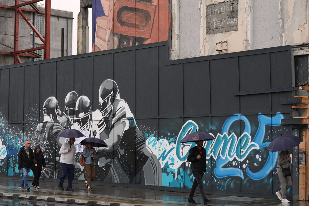 People walk past a temporary NFL football mural ahead of the NFL football match between Minnesota Vikings and Pittsburgh Steelers in Dublin, Saturday, Sept. 27, 2025.(AP Photo/Frank Augstein)