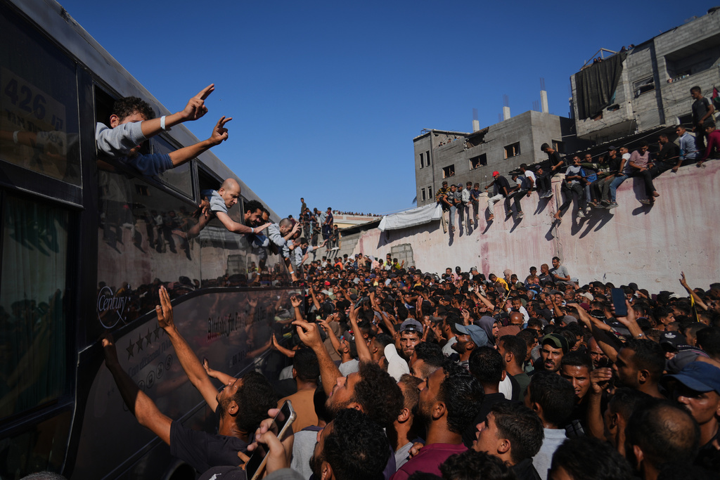 People gather to greet freed Palestinian prisoners arriving on buses in the Gaza Strip after their release from Israeli jails under a ceasefire agreement between Hamas and Israel, outside Nasser Hospital in Khan Younis, southern Gaza Strip, Monday, Oct. 13, 2025. (AP Photo/Abdel Kareem Hana)