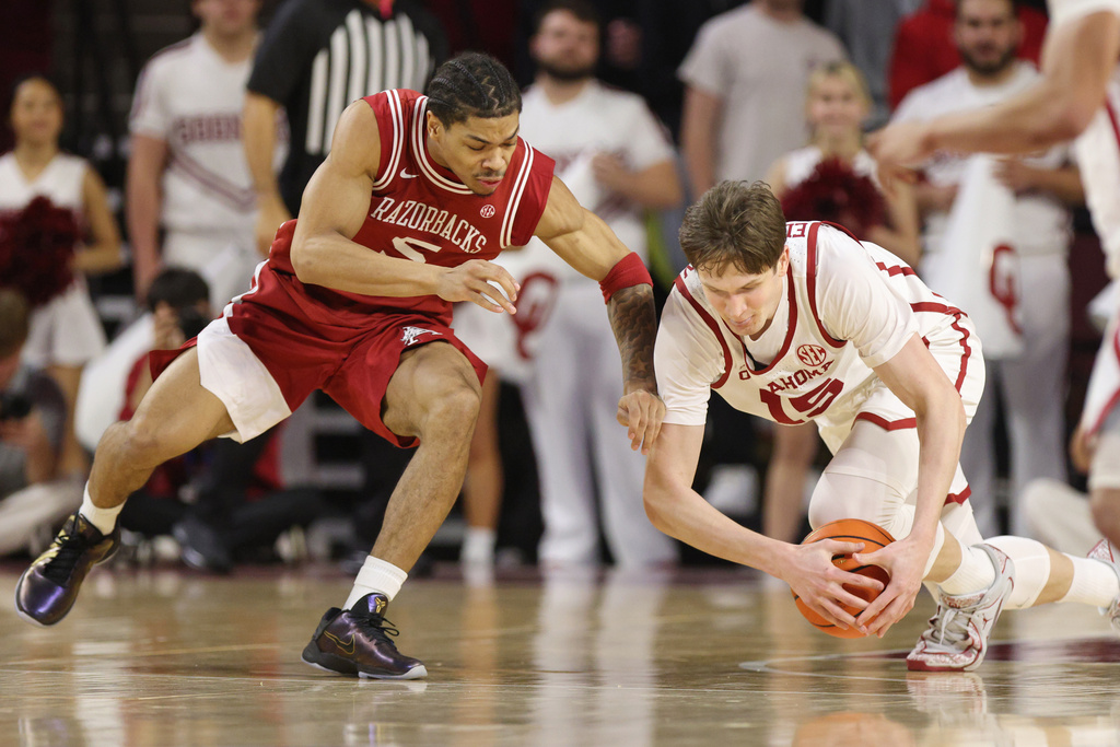 Oklahoma center Kirill Elatontsev, right, tries to secure the ball next to Arkansas guard Darius Acuff Jr., left, during the first half of an NCAA college basketball game Tuesday, Jan. 27, 2026, in Norman, Okla. (AP Photo/Nate Billings)