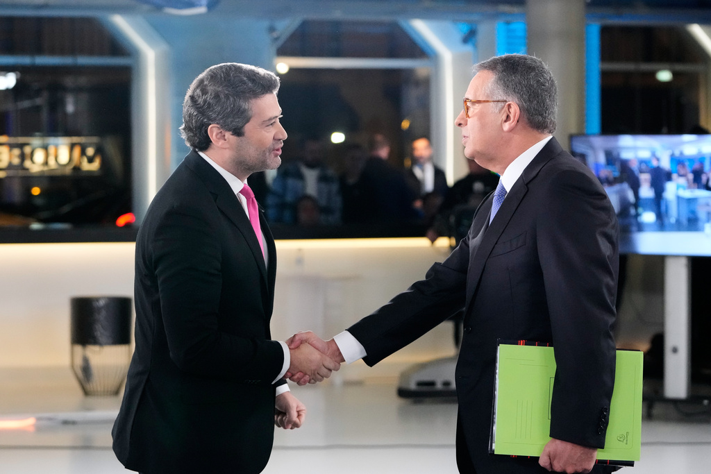 Presidential candidates Antonio Jose Seguro, of the center-left Socialist Party, right, and Andre Ventura, of the populist Chega party, shake hands before a television debate ahead of the Feb. 8 presidential election, in Lisbon, Tuesday, Jan. 27, 2026. (AP Photo/Armando Franca)