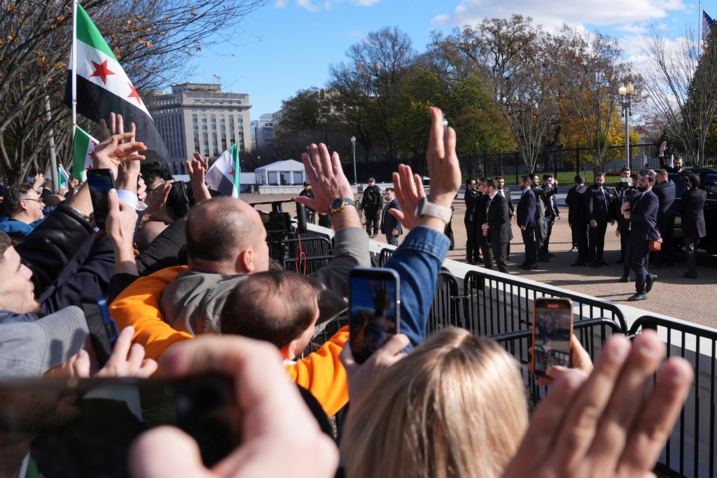 Syria's President Ahmed al-Sharaa, far right, waves to supporters from a vehicle outside of the White House, Monday, Nov. 10, 2025, in Washington, following al-Sharaa's meeting with President Donald Trump. (AP Photo/Jacquelyn Martin)