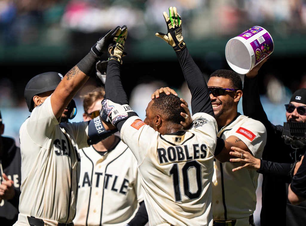 From left to right, Seattle Mariners' Jhonny Pereda, Colt Emerson, Victor Robles and Julio Rodriguez celebrate after a baseball game against the Arizona Diamondbacks, Sunday, May 31, 2026, in Seattle. (AP Photo/Stephen Brashear)