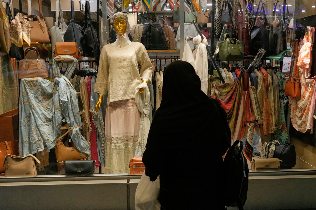 A woman looks at the window display a women's clothing shop in northern Tehran, Iran, Sunday, May 10, 2026. (AP Photo/Vahid Salemi)