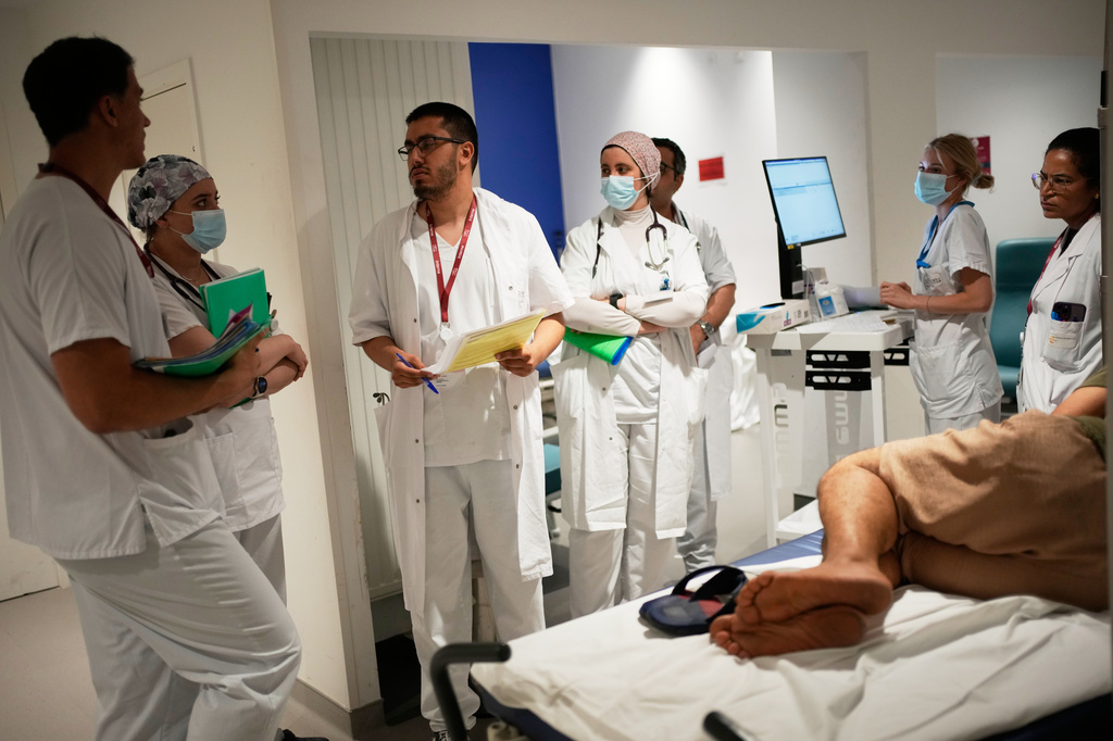Doctors and nurses take care of a patient at the emergency department of the Paris-Saclay Hospital, outside Paris, Tuesday June 30, 2026. (AP Photo/Christophe Ena )