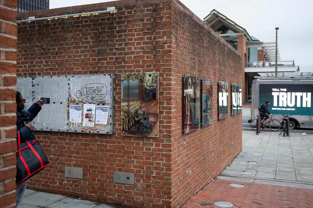 FILE - An attendee photographs a still-missing section of signs as people gather for a rally celebrating the reinstallation of a slavery exhibit at the President's House Site in Philadelphia on Feb. 19, 2026, in Philadelphia. (AP Photo/Joe Lamberti, File)