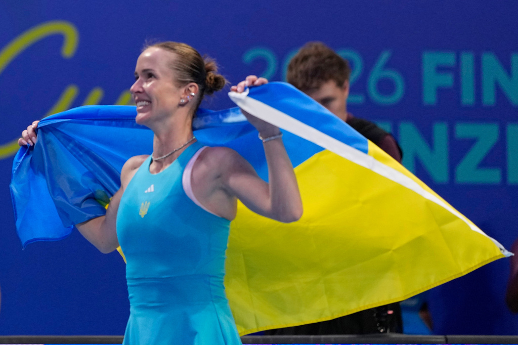 Elina Svitolina of Ukraine celebrates with the Ukraine flag after defeating Jasmine Paolini of Italy during the semifinal match of the Billie Jean King Cup in Shenzhen in southern China's Guangdong province, Saturday, Sept. 26, 2026. (AP Photo/Andy Wong)