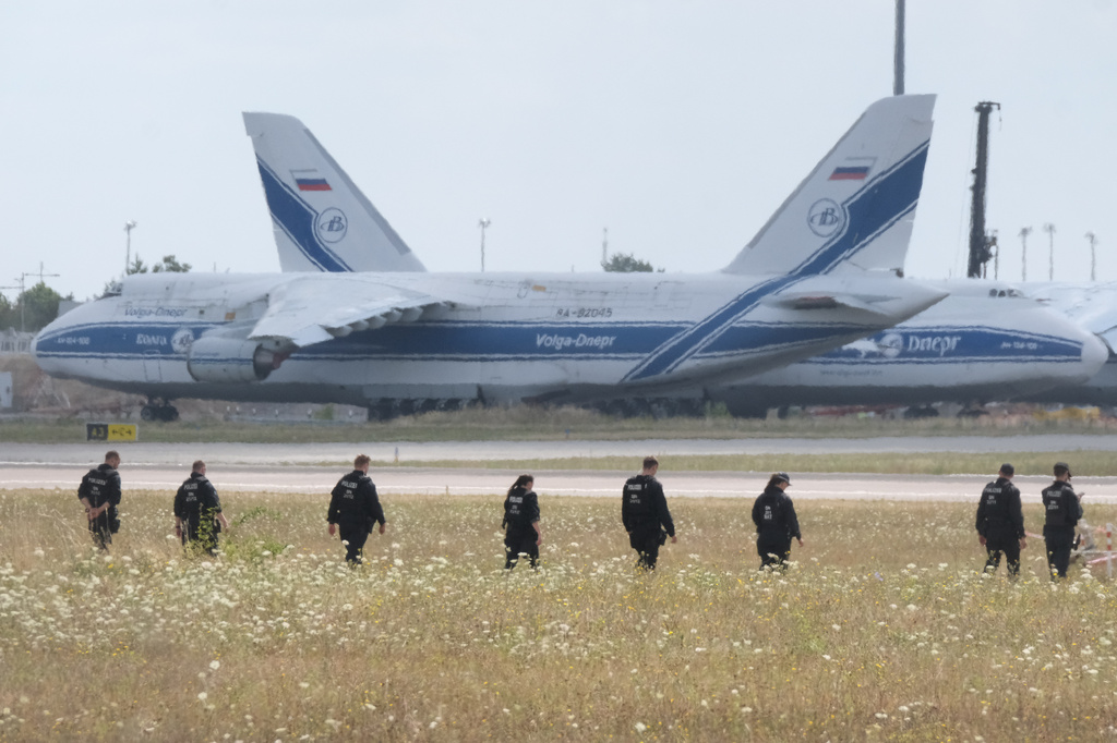 Police officers are walking across a field on the grounds of Leipzig Airport, in Schkeuditz, Germany, Friday, Aug. 7, 2026, searching for a drone that may be connected to a suspected attack. (Sebastian Willnow/dpa via AP)