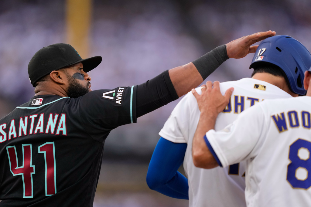 Arizona Diamondbacks first baseman Carlos Santana, left, pats Los Angeles Dodgers' Shohei Ohtani on the head after Ohtani walked during the first inning of a baseball game Saturday, March 28, 2026, in Los Angeles. (AP Photo/Mark J. Terrill)