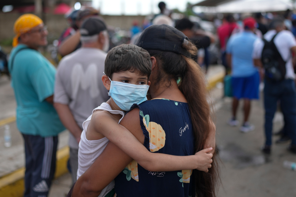 Ogleisys Cisneros holds her son, Santiago Medina, while waiting in line for government humanitarian aid, days after an earthquake struck in La Guaira, Venezuela, Tuesday, June 30, 2026. (AP Photo/Matias Delacroix)
