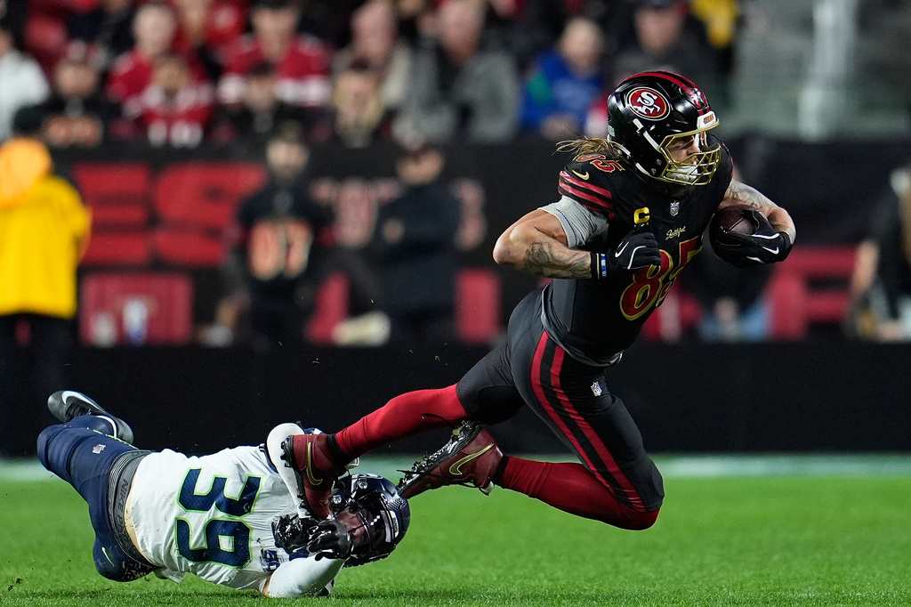 FILE - San Francisco 49ers tight end George Kittle, right, is tackled by Seattle Seahawks safety Ty Okada (39) during the second half of an NFL football game in Santa Clara, Calif., Jan. 3, 2026. (AP Photo/Godofredo A. Vásquez, File)