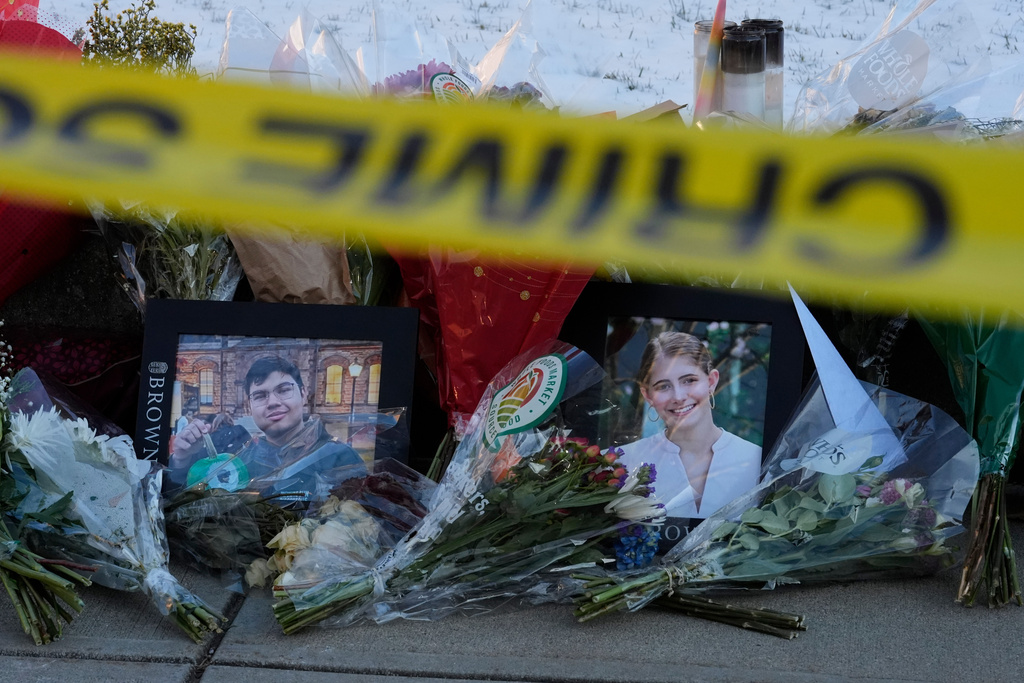 Photos of Brown University shooting victims Mukhammad Aziz Umurzokov, left, and Ella Cook, are seen amongst flowers at a makeshift memorial outside the Engineering Research Center, Tuesday, Dec. 16, 2025, in Providence, R.I.(AP Photo/Robert F. Bukaty)
