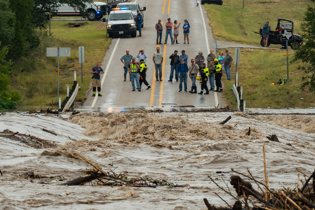 People gather to watch as the Perdenales River floods Ranch Road 1623 in Stonewall, Texas, Thursday, July 16, 2026. (Mikala Compton/Austin American-Statesman via AP)