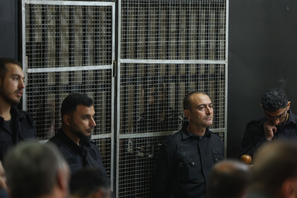 Suspects stand inside a holding cell during Syria's first public trial related to deadly clashes in March along the country's coastal provinces, at the Palace of Justice in Aleppo, Syria, Tuesday, Nov. 18, 2025. (AP Photo/Ghaith Alsayed)