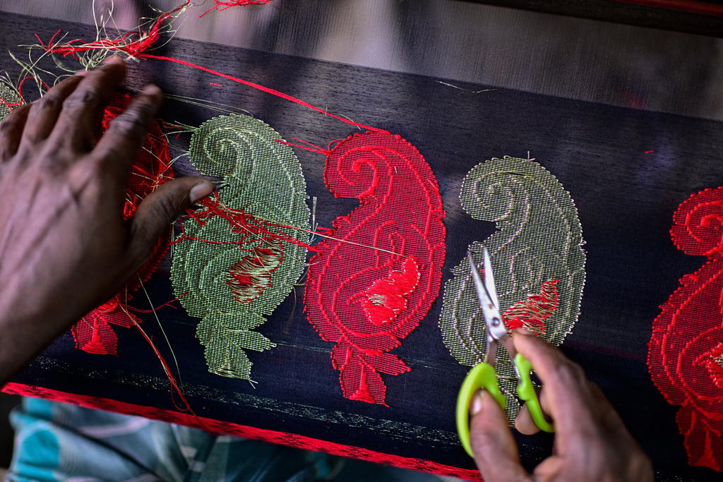An artisan cuts excess thread from a Tangail saree at a weaving workshop in Tangail District, Bangladesh, Nov. 5, 2025. (AP Photo/Mahmud Hossain Opu)