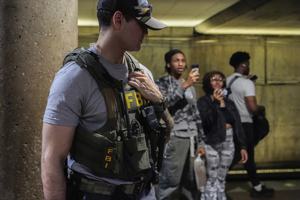 An FBI agent stands by as District of Columbia Metro Transit Police Department and Metropolitan Police Department officers detain three people at L'Enfant Plaza metro station, Thursday, Aug. 21, 2025, in Washington. (AP Photo/Julia Demaree Nikhinson)