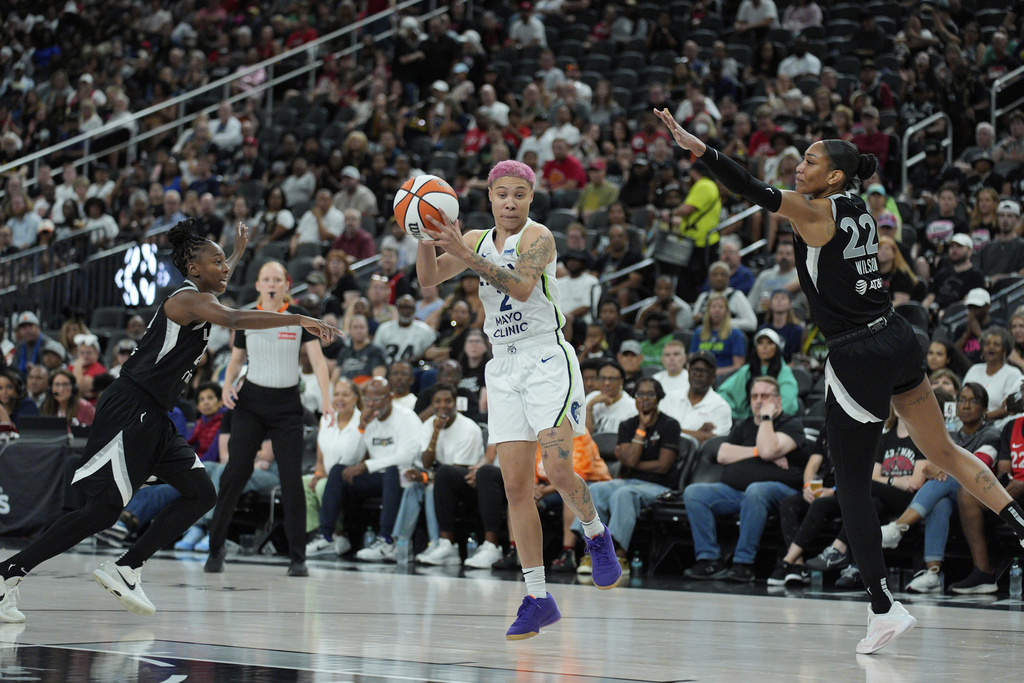 Minnesota Lynx guard Natisha Hiedeman (2) drive between Las Vegas Aces center A'ja Wilson (22) and Las Vegas Aces guard Jewell Loyd (24) during the second half of a WNBA basketball game Thursday, Sept. 4, 2025, in Las Vegas. (AP Photo/John Locher)