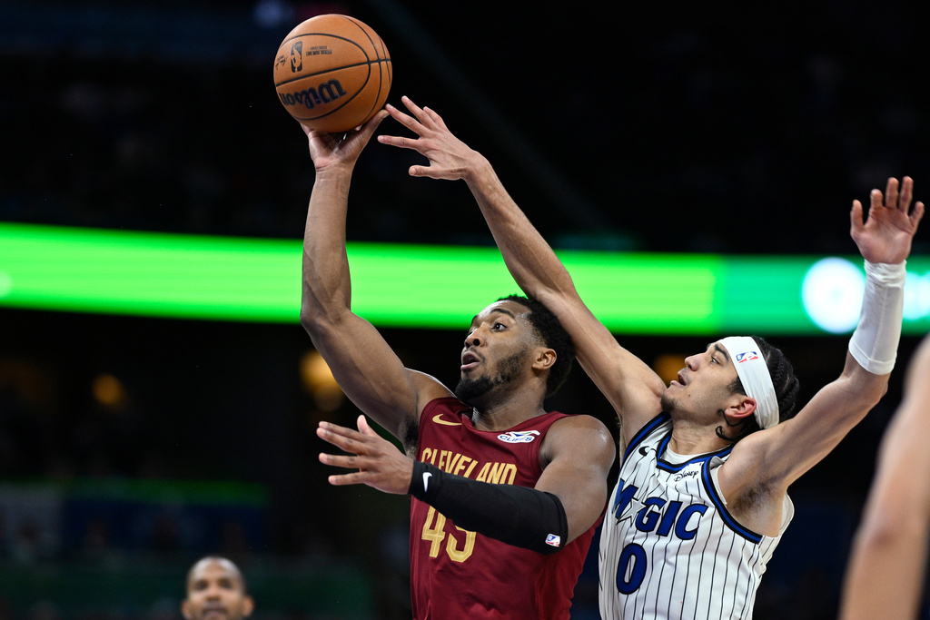 Cleveland Cavaliers guard Donovan Mitchell, second from right, goes up to shoot as Orlando Magic guard Anthony Black (0) defends during the second half of an NBA basketball game, Saturday, Jan. 24, 2026, in Orlando, Fla. (AP Photo/Phelan M. Ebenhack)