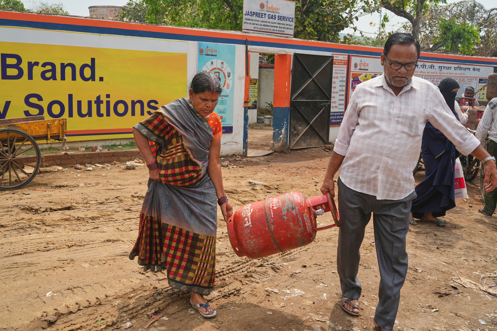 An elderly couple carries a gas cylinder to their home after collecting it from a depot, in New Delhi, Thursday, March 19, 2026. (AP Photo/Manish Swarup)