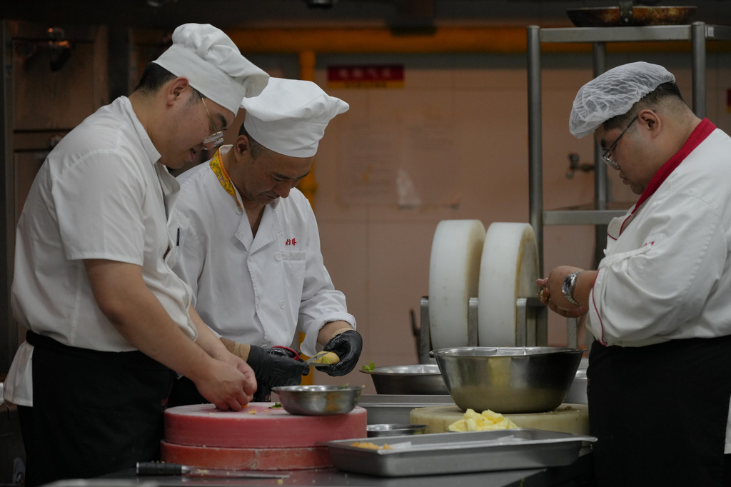 Chefs prepare dishes inside a kitchen of Fangshan Restaurant in Beijing on July 23, 2026. (AP Photo/Andy Wong)