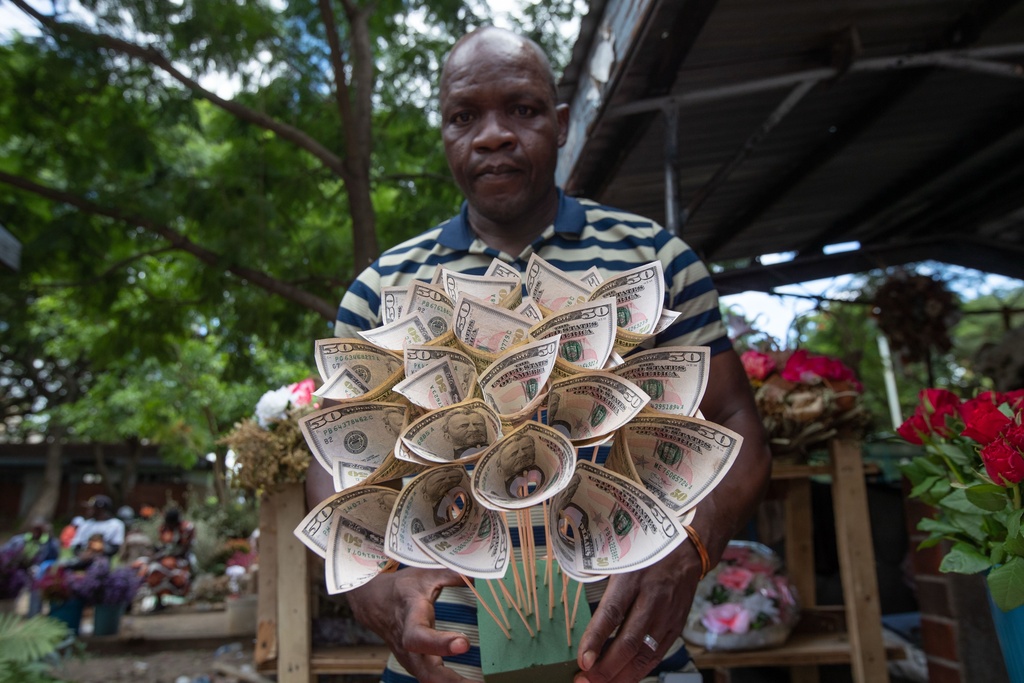 Florist Tongai Mufandaedza holds a money bouquet designed for Valentine's Day at his stall in Harare, Zimbabwe, Tuesday, Feb. 10, 2026. (AP Photo/Aaron Ufumeli)