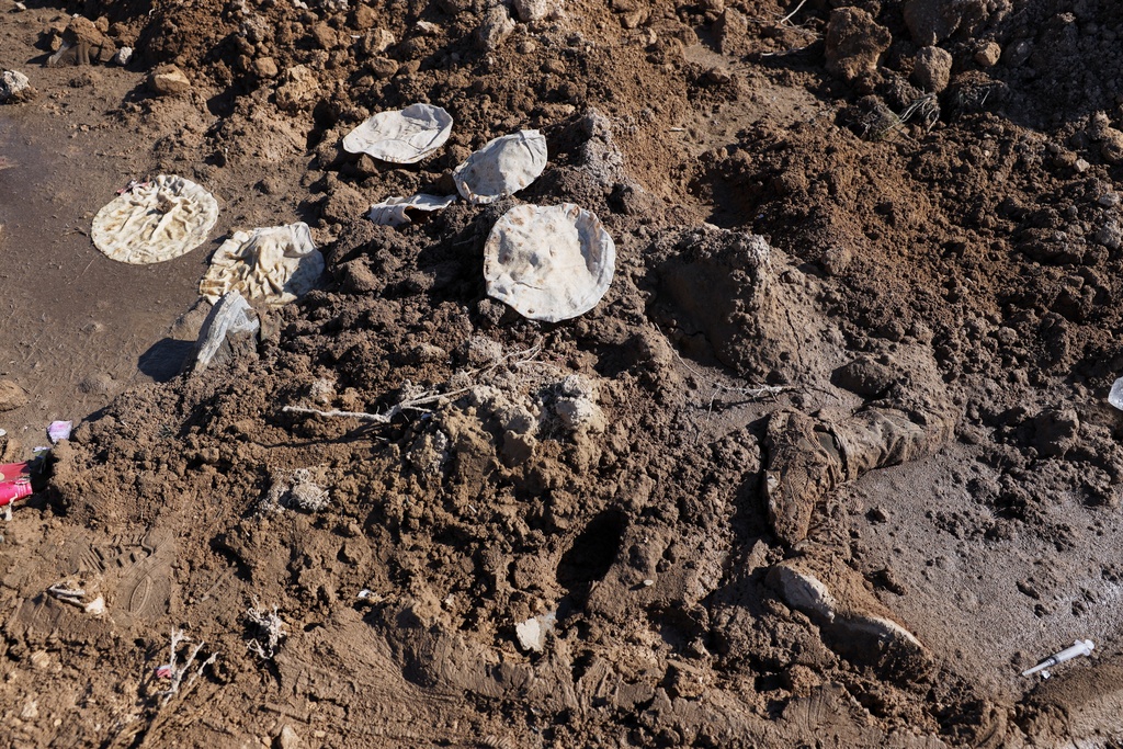 A body lies covered by dirt on the side of the road between government-controlled Raqqa and SDF-controlled Hassakeh in northeastern Syria, Tuesday Jan. 20, 2026. (AP Photo/Omar Albam)