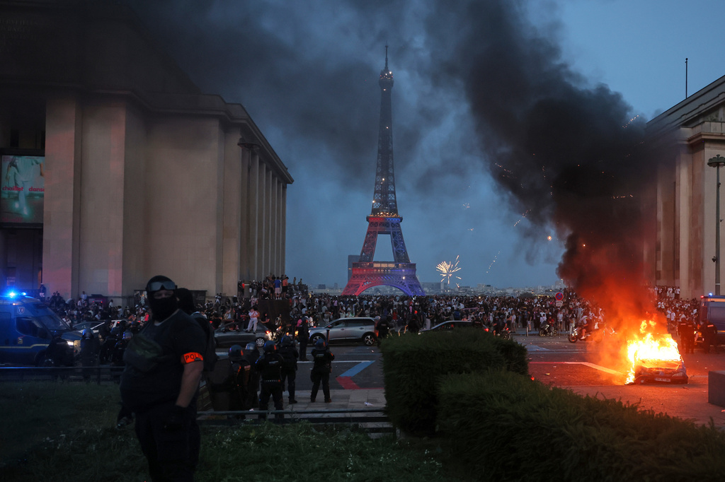 A car burns and fireworks explode as police watch PSG supporters celebrate in Paris, Saturday, May 30, 2026 after the Champions League final soccer match between Paris Saint-Germain and Arsenal that's being played in Budapest., PSG won the game. (AP Photo/Thomas Padilla)