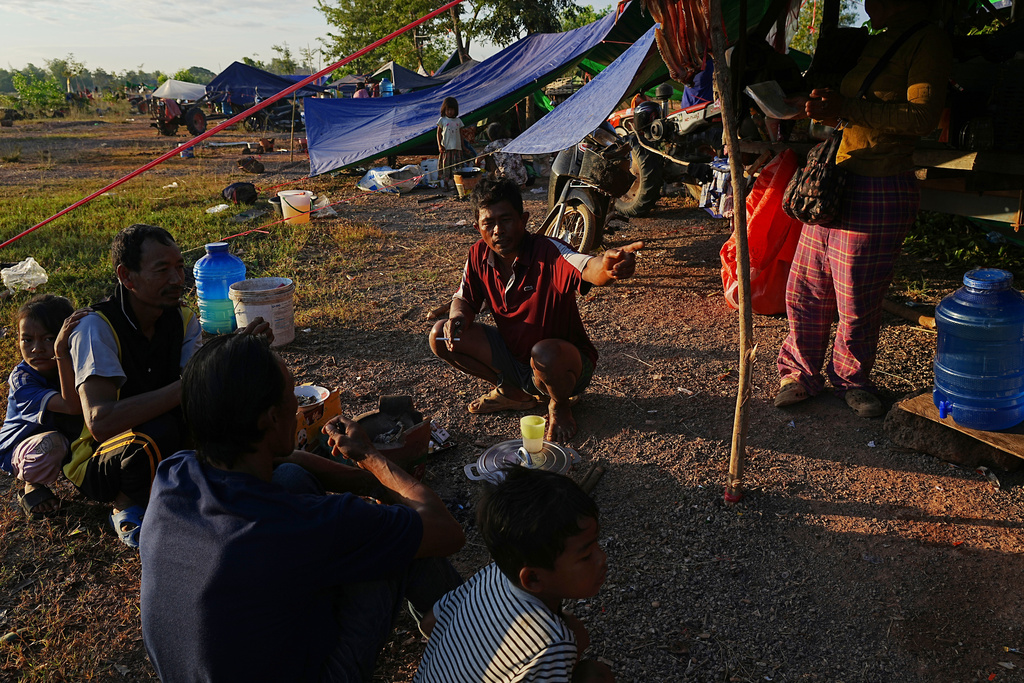 People warm themselves around a bonfire as they take refuge at Wat Chroy Neangoun's Buddhist pagoda in Siem Reap province, Cambodia Friday, Dec. 12, 2025, after fleeing from home following fighting between Thailand and Cambodia over territorial claims. (AP Photo/Heng Sinith)
