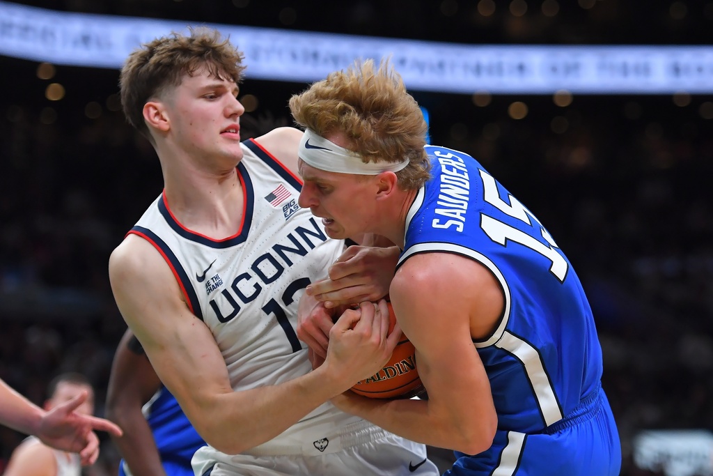UConn center Eric Reibe and BYU guard Richie Saunders grapple for control of the ball in the first half of an NCAA college basketball game, Saturday, Nov. 15, 2025, in Boston. (AP Photo/Steven Senne)