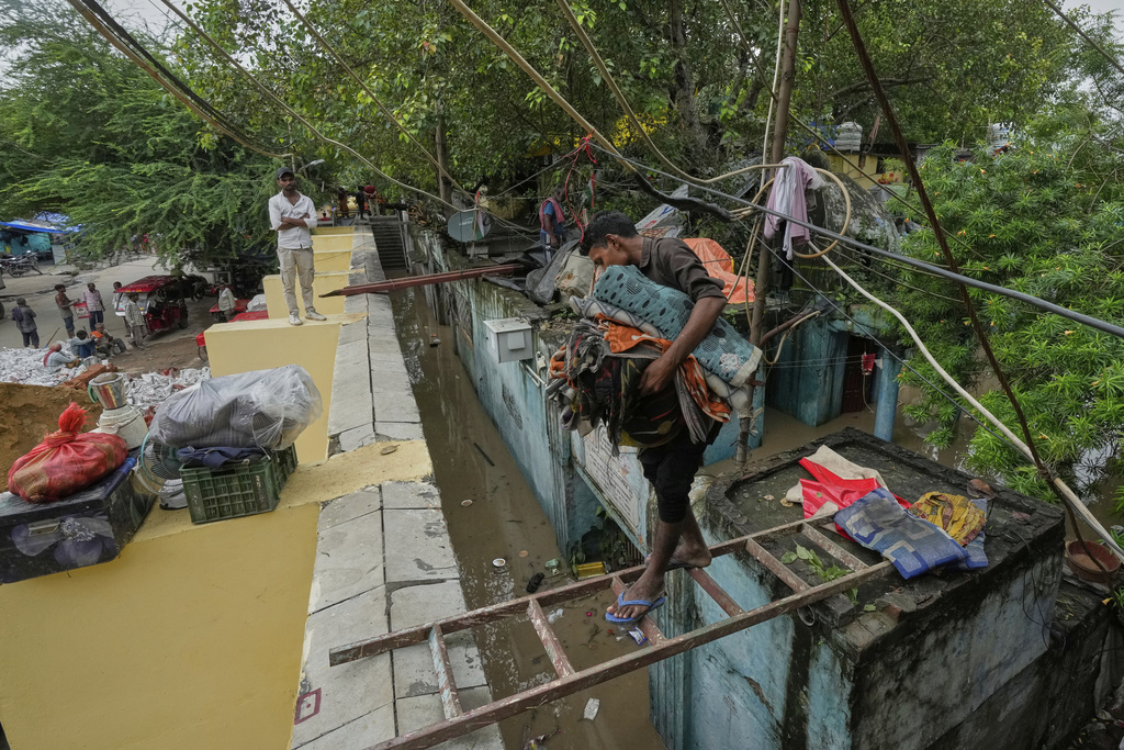 A resident moves his belongings to a safer place after the river Yamuna, swollen by incessant rain in the higher regions, overran its banks, in New Delhi, India, Tuesday, Sept. 2, 2025. (AP Photo/Manish Swarup)