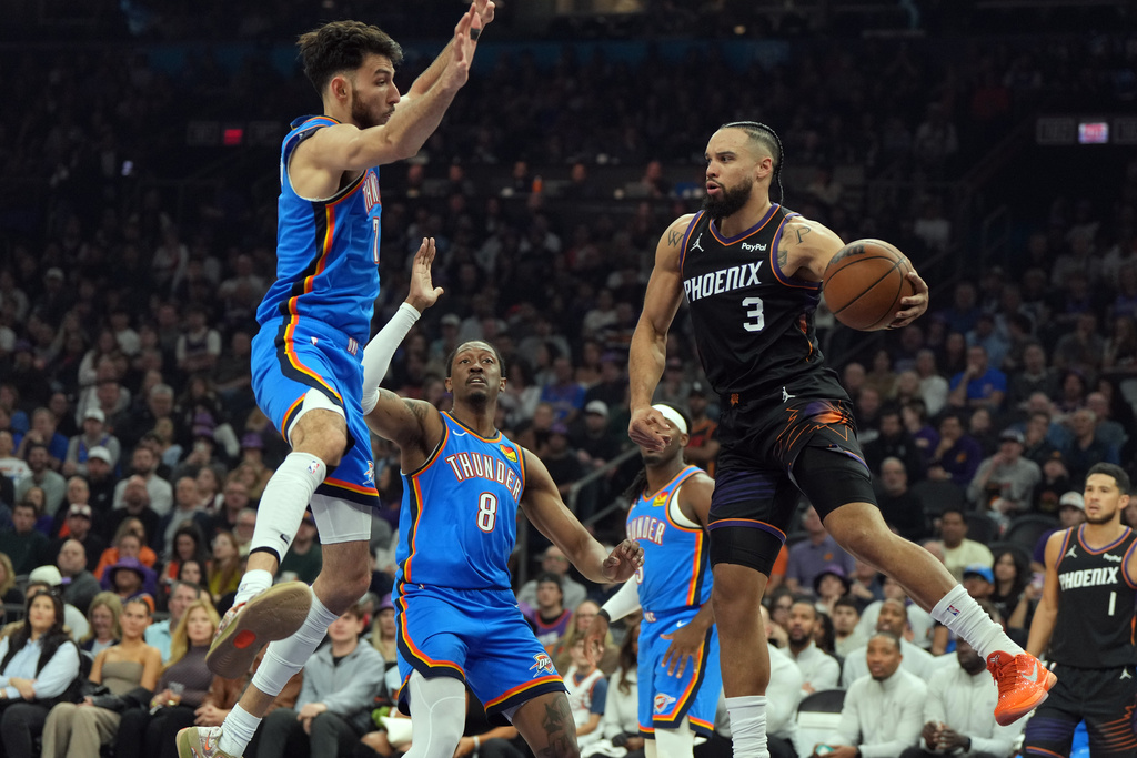 Phoenix Suns forward Dillon Brooks (3) drives against Oklahoma City Thunder center Chet Holmgren, left, and guard Jalen Williams (8) during the first half of an NBA basketball game, Sunday, Jan. 4, 2026, in Phoenix. (AP Photo/Rick Scuteri)