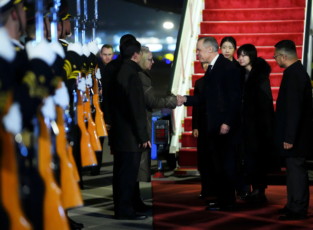 Prime Minister Mark Carney shakes hands with Canadian Ambassador to China Jennifer May as he is officially welcomed to Beijing, China on Wednesday, Jan. 14, 2026. (Sean Kilpatrick /The Canadian Press via AP)