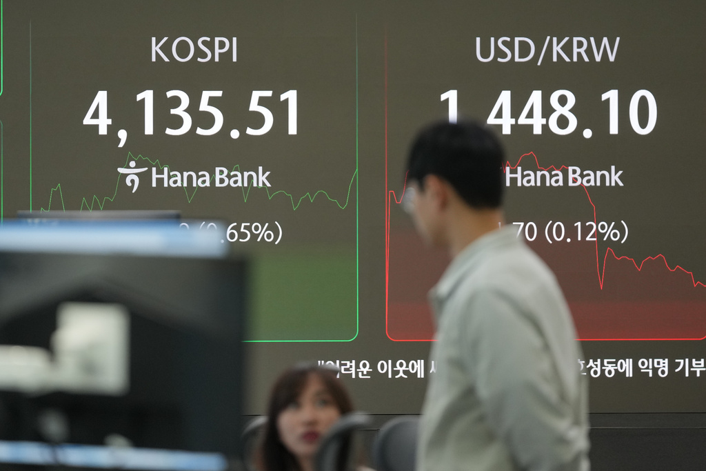 Dealers talk near the screens showing the Korea Composite Stock Price Index (KOSPI), left, and the foreign exchange rate between U.S. dollar and South Korean won at a dealing room of Hana Bank in Seoul, South Korea, Friday, Dec. 26, 2025. (AP Photo/Lee Jin-man)