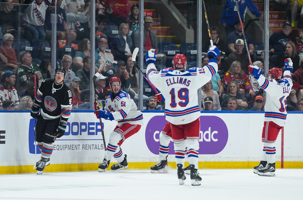 Kitchener Rangers' Jared Woolley (51), Luke Ellinas (19) and Haeden Ellis (13) celebrate Woolley's goal as Kelowna Rockets' Shane Smith (9) skates past during the second period of a Memorial Cup hockey game in Kelowna, British Columbia, Friday, May 22, 2026. (Darryl Dyck/The Canadian Press via AP)