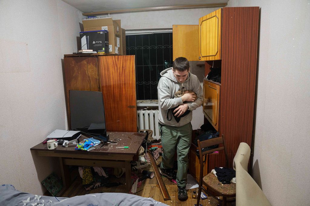A man carries his bunny inside a house damaged after a Russian strike on residential area in Kyiv, Ukraine, on Thursday, April 16, 2026. (AP Photo/Evgeniy Maloletka)