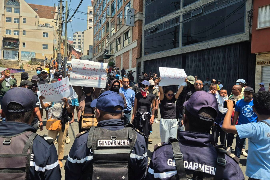 Demonstrators hold up placards reading "water and electricity are basic human rights," "Malagasy people, wake up," "Let's not remain in the dark with our yellow cans" in Antananarivo, Madagascar, Thursday, Sept. 25, 2025. (AP Photo/Sarah Tetaud)