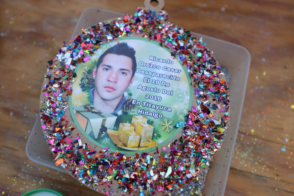 A photograph of Ricardo Orozco, who disappeared on August 19, 2016 in Tizayuca, Hidalgo state, decorates a Christmas ornament to hang on the Tree of Hope during an event organized by the diocese of Ecatepec at the Church of the Sacred Heart of San Cristobal in Ecatepec, State of Mexico, Monday, Nov. 17, 2025. (AP Photo/Ginnette Riquelme)