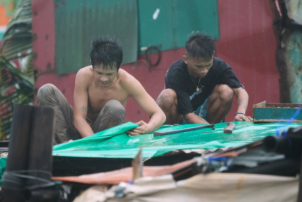 Residents reinforce their roof as strong winds due to Typhoon Fung-wong continue at a coastal village on Monday, Nov. 10, 2025, in Navotas, Philippines. (AP Photo/Aaron Favila)