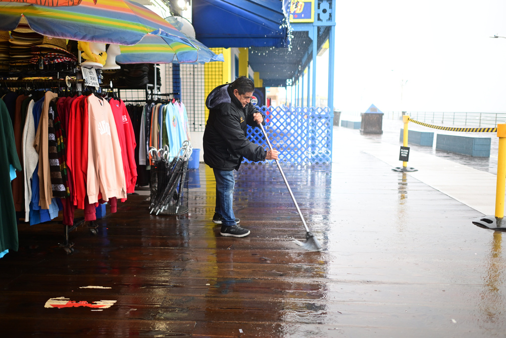 Miguel Lopez sweeps water from Marlene's Beachcomber on the Santa Monica pier Wednesday, Dec. 24, 2025, in Santa Monica, Calif. (AP Photo/Wally Skalij)