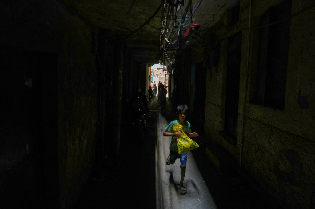A boy runs through a dark alley next to a restaurant and hotel building that caught fire early this morning in New Delhi, India, Wednesday, June 3, 2026. (AP Photo/Manish Swarup)