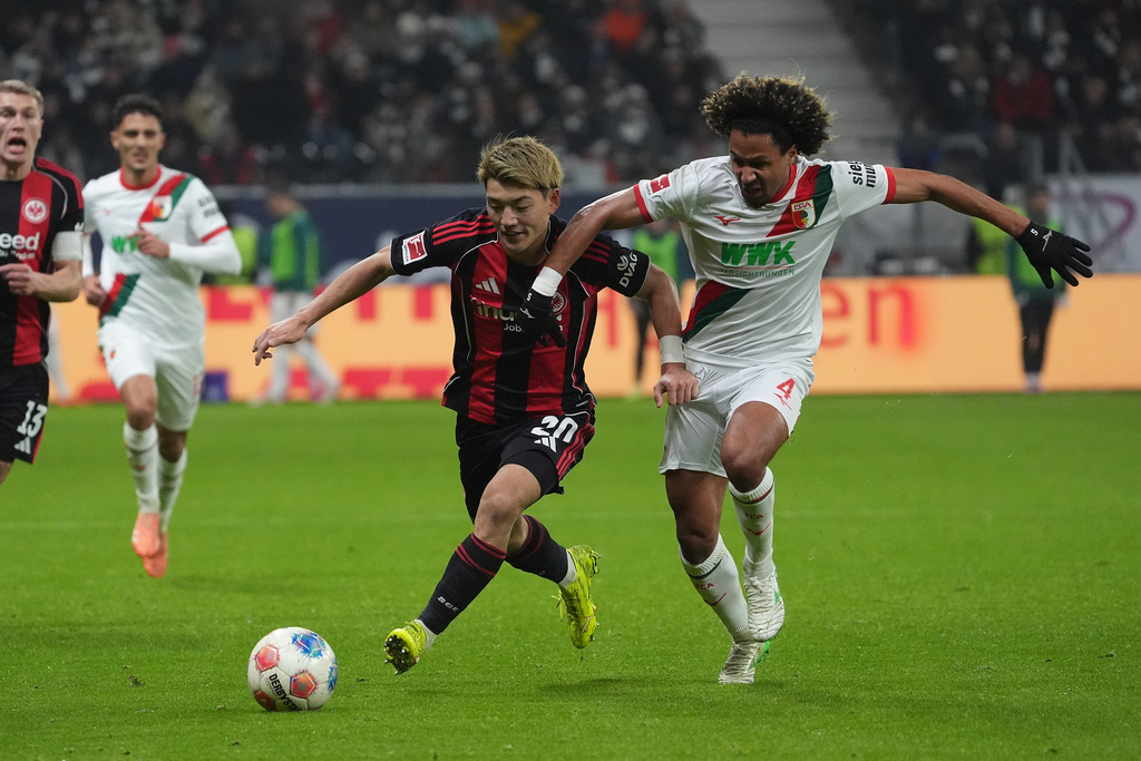 Frankfurt's Ritsu Doan, left, and Augsburg's Han-Noah Massengo, right, challenge for the ball during the German Bundesliga soccer match between Eintracht Frankfurt and FC Augsburg in Frankfurt, Germany, Saturday, Dec. 13, 2025. (Marc Schueler/dpa via AP)