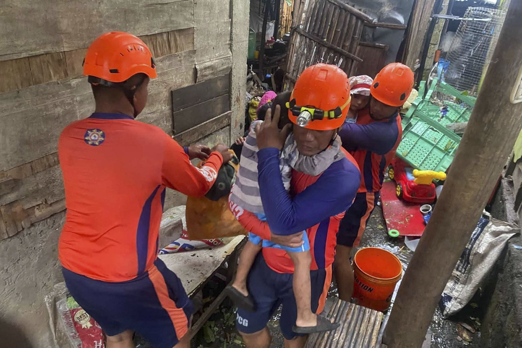 In this photo provided by the Philippine Coast Guard, rescuers evacuate residents to safer grounds Laurel, Batangas province, Philippines as Typhoon Fung-wong affects the country, Sunday Nov. 9 2025. (Philippine Coast Guard via AP)