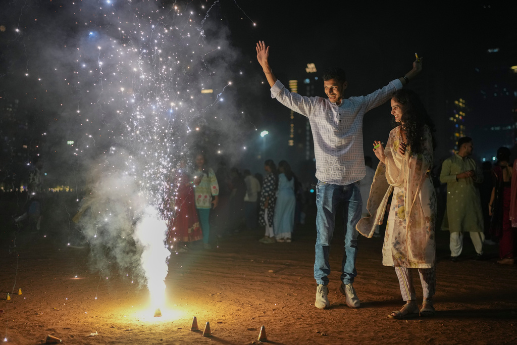 A family lights firecrackers during the Diwali festival of lights in Mumbai, India, Monday, Oct. 20, 2025. (AP Photo/Rafiq Maqbool)
