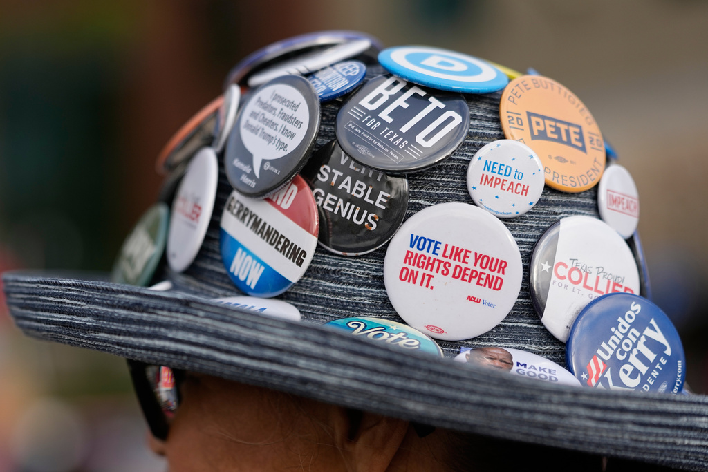 Pat Garris wears a hat full of political buttons outside a polling location Tuesday, March 3, 2026, in Spring, Texas. (AP Photo/David J. Phillip)